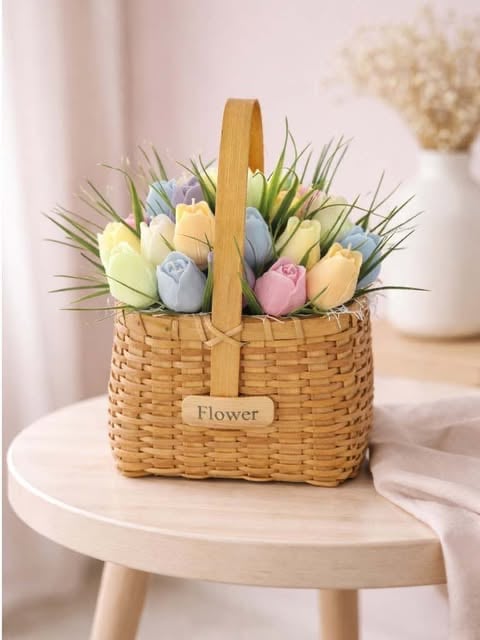 Woven wicker basket with wooden handle filled with colorful tulip flowers and green stems, labeled Flower, displayed on a round white table