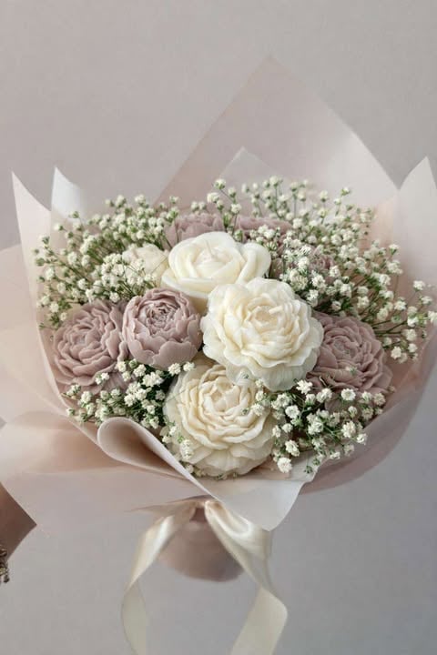 Elegant flower bouquet with cream and mauve roses surrounded by white babys breath, wrapped in blush paper with ribbon bow